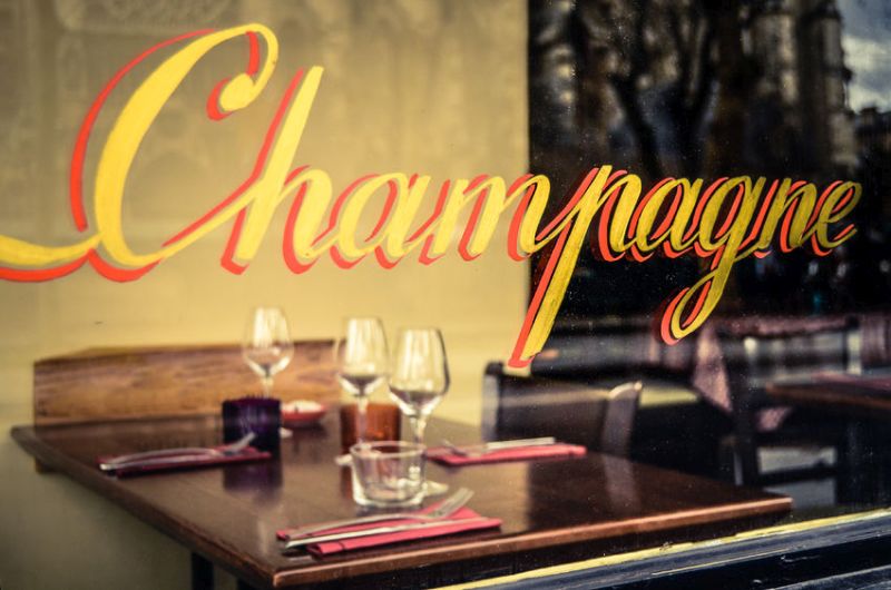 47249515 - paris restaurant with champagne sign in the window with place settings and wine glasses