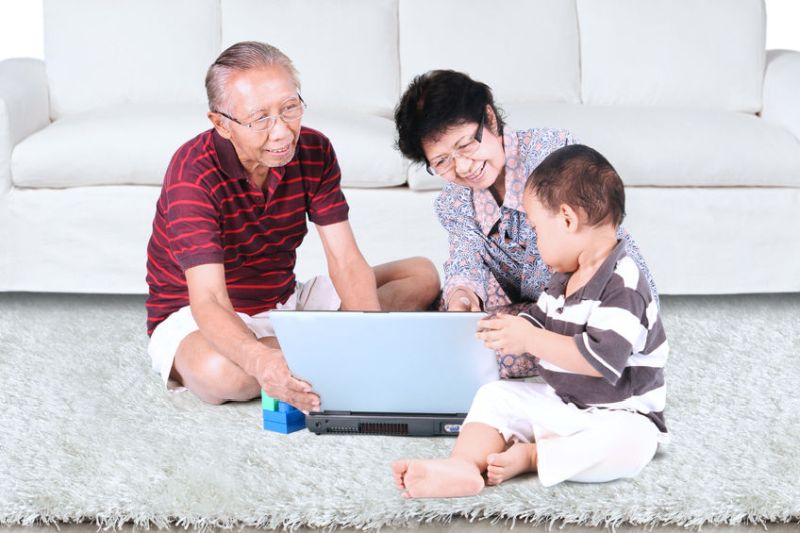 55759637 - grandmother and grandfather teach their grandson to use a laptop at home